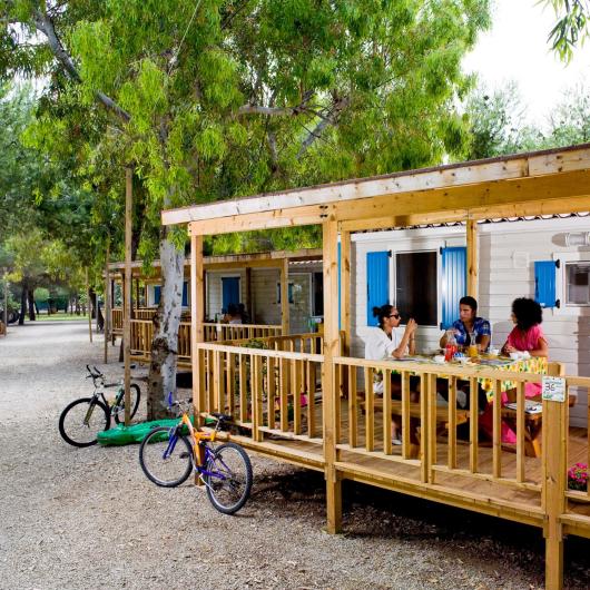 People sitting on a wooden porch at a campsite.